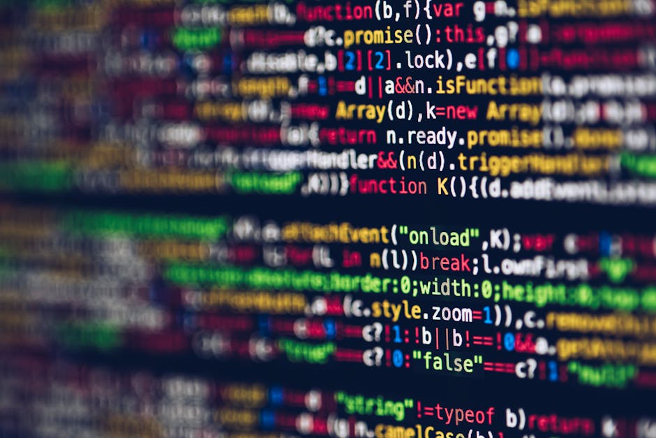 A close-up view of a person's hands operating a laptop computer on a dark surface. The laptop screen displays lines of programming code in a code editor, with syntax highlighting in green, blue, and w